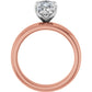 Profile view of a rose gold solitaire engagement ring with a raised silver-tone prong setting
